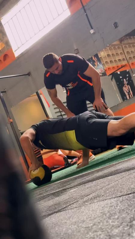 Aluno fazendo exercício no solo com acompanhamento do professor na Hardcore